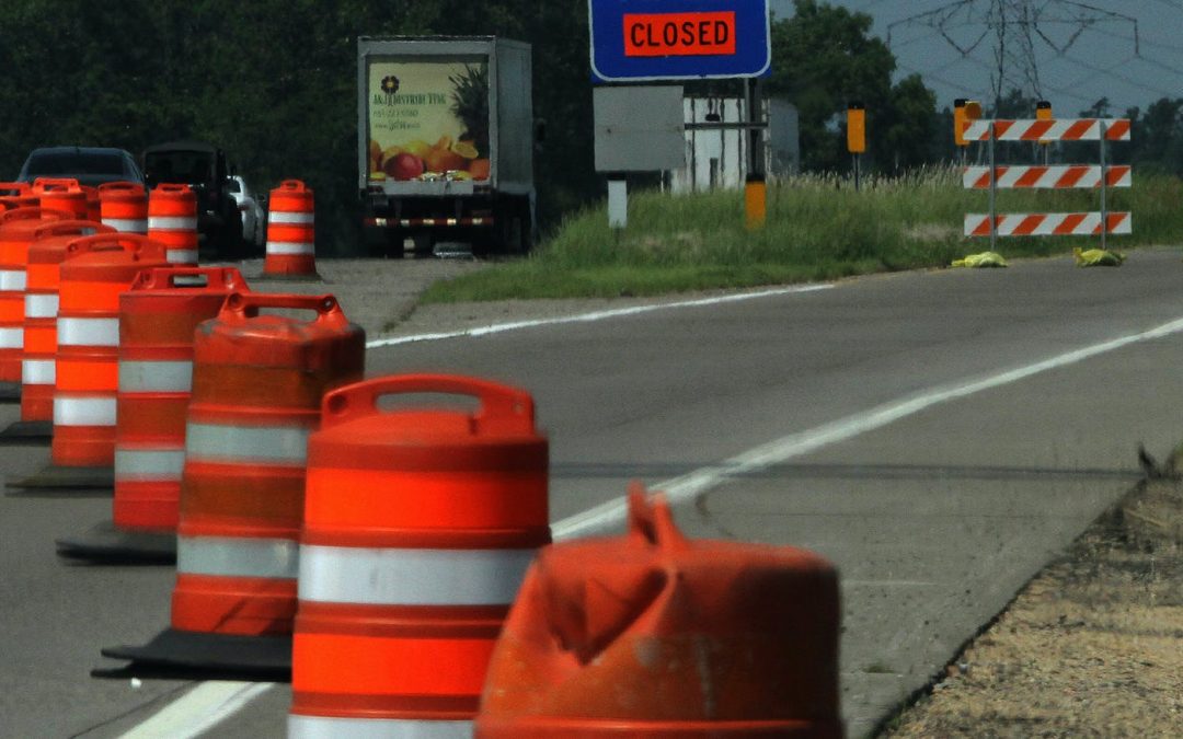 orange construction cones on highway merging traffic to one lane